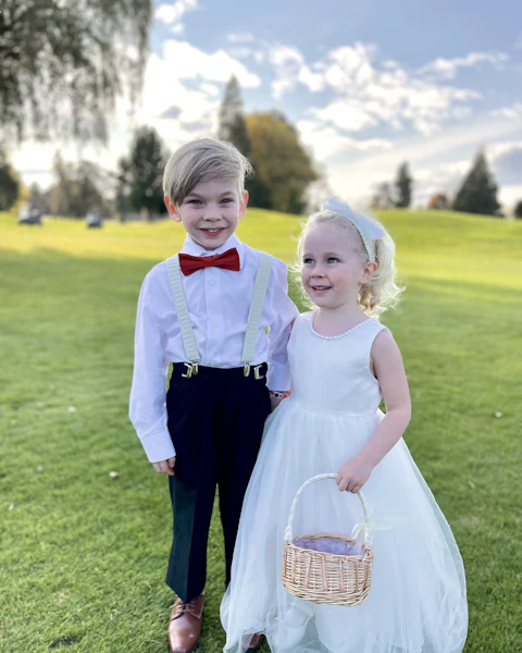 Un niño con pajarita roja y una niña vestida de blanco en el jardín